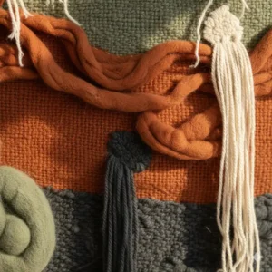 Close-up detail showing the rich embroidery and material of a textile hanging art work.