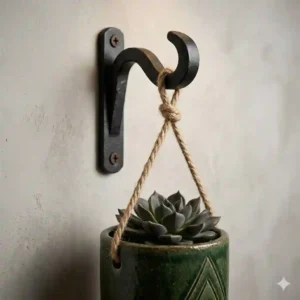 Close-up shot of a sturdy matte black iron wall hook holding a heavy ceramic flower pot holder.